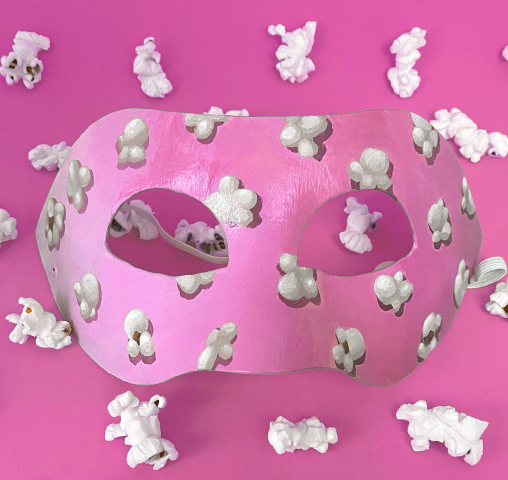 a pink mask with popcorn painted on it